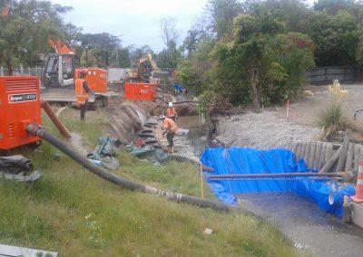 Photograph of dam with water being pumped around work area.
